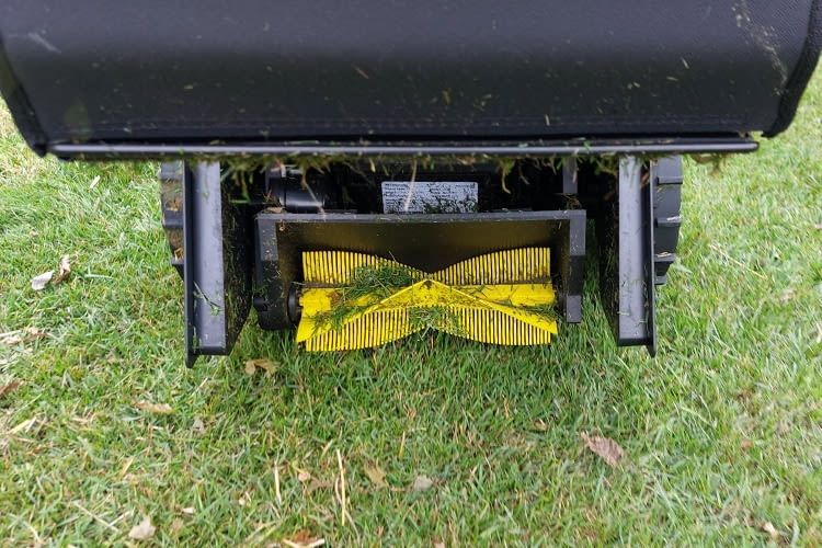 Mit dieser kleinen, gelben Bürste fegt YUKA Grünabfall vom Rasen